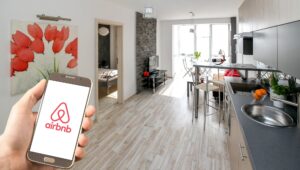 a clean kitchen in an airbnb with a hand showing the airbnb app on the mobile phone